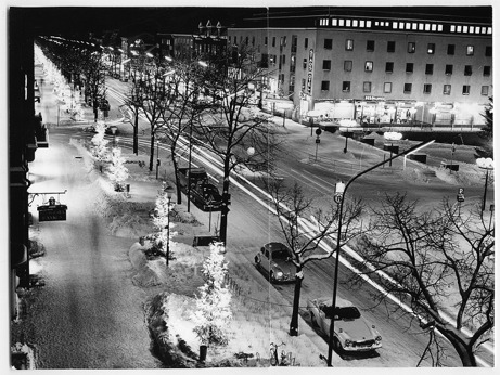 Foto över upplyst esplanad/centrumgata trafikerad av ett antal bilar. Foto över upplyst esplanad/centrumgata trafikerad av ett antal bilar.
