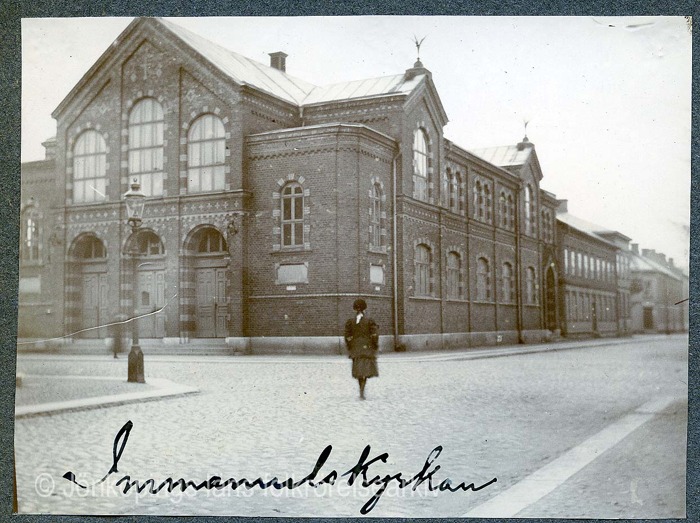 Svartvitt foto på Stor tegelbyggnad. På kullerstensgatan framför byggnaden syns ryggtavlan på en kvinna i mörka kläder. Foto ur Jönköpings hembygdsförening Gudmundsgillets arkiv. Svartvitt foto på Stor tegelbyggnad. På kullerstensgatan framför byggnaden syns ryggtavlan på en kvinna i mörka kläder. Foto ur Jönköpings hembygdsförening Gudmundsgillets arkiv.