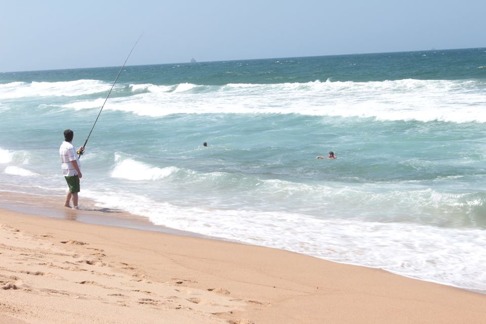 Två män badar på samma plats som en annan man fiskar vid Umhlanga, Durban. Detta är uppenbarligen inte en bra kombination eftersom fiskarens bete kan attrahera hajar till de två badande männen. Männen i vattnet utsätter sig för en onödig risk. Bild: David C. Bernvi. Två män badar på samma plats som en annan man fiskar vid Umhlanga, Durban. Detta är uppenbarligen inte en bra kombination eftersom fiskarens bete kan attrahera hajar till de två badande männen. Männen i vattnet utsätter sig för en onödig risk. Bild: David C. Bernvi.