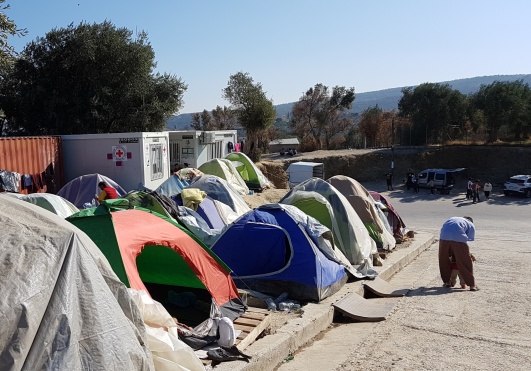Foto från okt 2019: tältsamling utanför murarna till Morias flyktingläger på Lesbos. Observera lastpallarna som lagts under tälten för att undvika regnvattnet som ibland forsade nedför sluttningen. I barackerna till vänster bedrev volontärer rådgivning kring medicinska frågor och asylärenden. Allt är nu nedbrunnet. Foto: Lisa Norgren Benedictsson Foto från okt 2019: tältsamling utanför murarna till Morias flyktingläger på Lesbos. Observera lastpallarna som lagts under tälten för att undvika regnvattnet som ibland forsade nedför sluttningen. I barackerna till vänster bedrev volontärer rådgivning kring medicinska frågor och asylärenden. Allt är nu nedbrunnet. Foto: Lisa Norgren Benedictsson