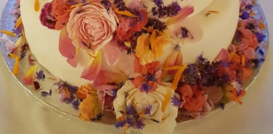Tårtfatet dekorerades med ätbara blommor tillsammans med bröllopstårtan Tårtfatet dekorerades med ätbara blommor tillsammans med bröllopstårtan