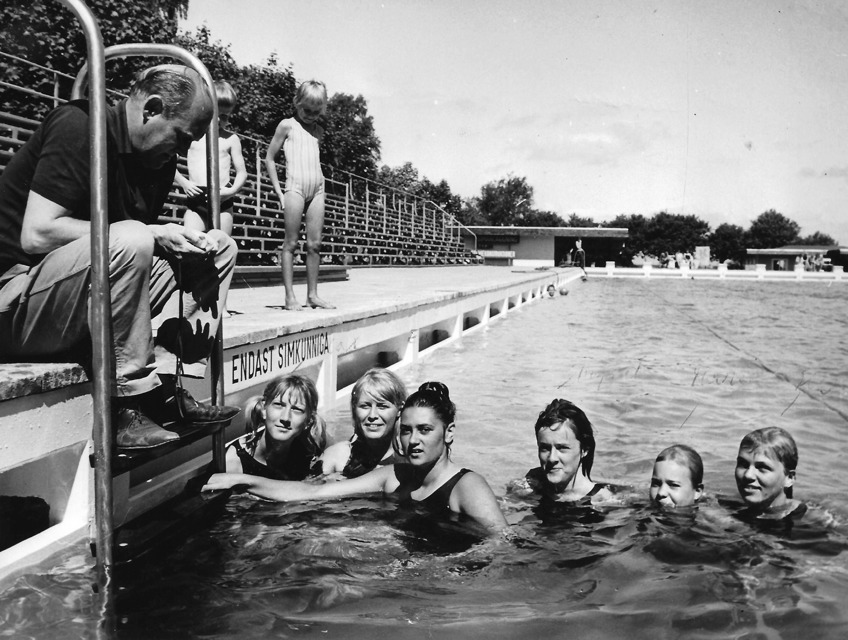 Birger Buhre på bassängkanten i Malen/Båstad med i vattnet frv. Marianne Stridh, Evy Sätherström, Marianne Sjöström, Ingrid Ahlström, Marie Nilsson och Lisbeth Sandgren.