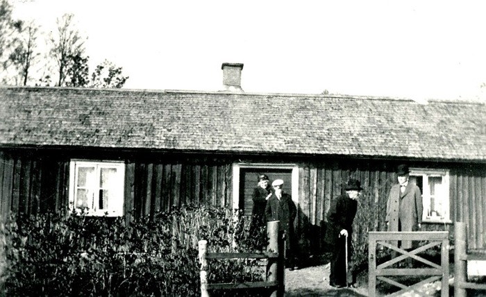 A. 32 (1) Bäckedalen runt 1930. Gamla stugan i Bäckedalen, där Petter Lindqvist bodde och troligen undervisade skolbarn under 1830-40-talen. På bilden står från vänster Petters sonsons hustru, ett barnbarnsbarn, Per Hålltorp (med käpp) omkring 95 år gammal och Arvid på Hålltorp, son tilll Per. Naturnamnet Bäckedalen kommer sig naturligt av den djupa bäckravin som finns inom området som grundar upp fram emot Ljungstorspsvägen på Flinkebackens mark. Det lär ha funnits en skvaltkvarn nära platsen på Flinkebackens mark - en kvarn för husbehovs-malning. Det finns på karta 1882 en damm-markering på den intäkten. Bäckens ravin har också naturligt skapat gränserna för de många små intäkter och boplatser som skapades här - främst under 1800-talet. Här bodde också David och Josefina Roth ("Fina"). Stugan revs 1938 och den nuvarande uppfördes till stor del av timmer från det rivna hemmanet Sten. Insatt av Kent Friman, 2014-02-24. Läs mer på www.ljungstorpshistoria.se!