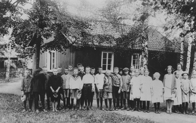 Skolfoto från Varnhem omkring 1925, den s.k mellanskolan låg i kyrkeparken med Kyrkogatan i bakgrunden och det gamla stallet med offentliga toaletter (och skoltoalett).