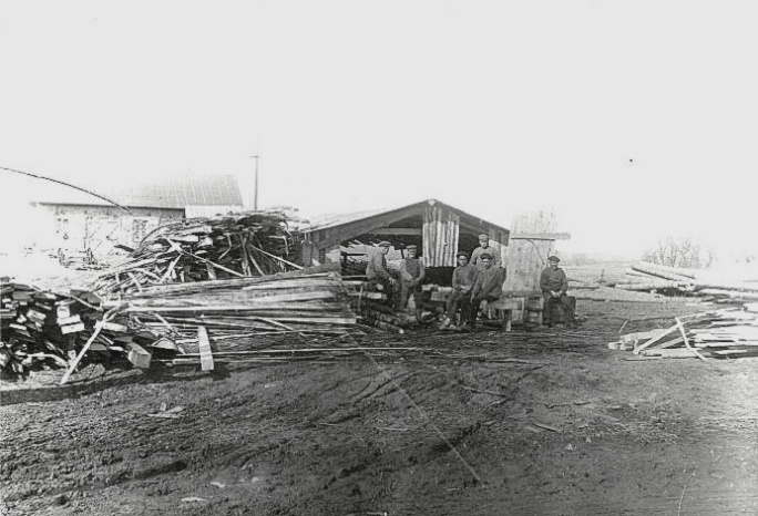Arbete vid Tomtens sågverk framför smedjan 1920-tal. Bilden från Skarke-Varnhems Hembygdsförenings digitala arkiv. På bilden  från höger Tomta-sme'n s son Allan Stålheim, Tomta-sme'n själv och några anställda.