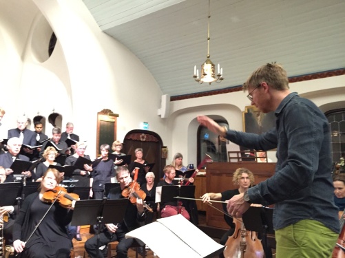 Conductor David Åberg rehearsing with choir and orchestra.