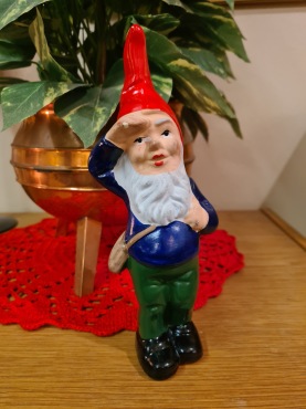 Stående saluterande tomte med väska. Höjd 21 cm. Liten nagg på fingret, i övrigt gott skick. Saknar märkning.  75 SEK