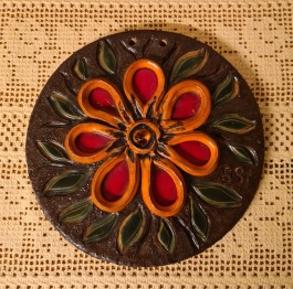 Rund keramiktavla med motiv av orange blomma. Diam. 19 cm. Fint skick. Otydlig  signatur. 70 SEK