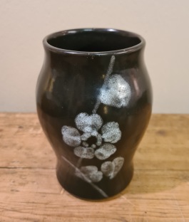 Svart vas med grå blomma (tysk?). Höjd 14 cm. Fint skick. 50 SEK