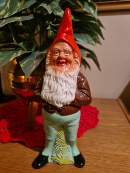 Stående tomte med brun jacka och blågröna byxor. Höjd 24 cm. Lagade ben, i övrigt ok. 90 SEK