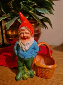 Stående tomte vid korg. Höjd 18 cm, bredd ca 13 cm. Korgen lagad, i övrigt gott skick. 90 SEK