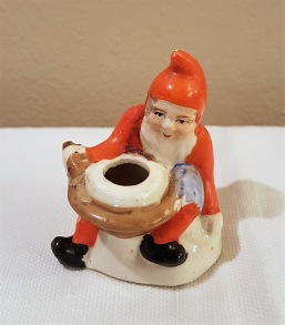 Liten tomte vid grötgryta - ljushållare. Höjd 6 cm. Liten skada vid sleven, annars ok. 60 SEK
