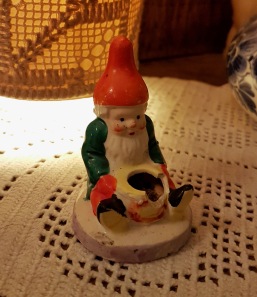 Äldre sittande tomte med trasig ljushållare (märkt import). Höjd 7 cm. Förutom den trasiga ljushållare är skicket bra. 40 SEK