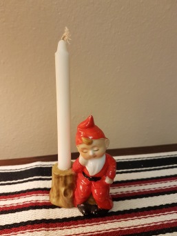 Liten vilande tomte vid stubbe/ljushållare. Bredd 6 cm, höjd 8,5 cm. Fint skick. 60 SEK