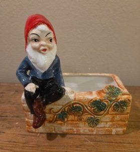 Tomte sittande på mur. Längd ca 12 cm, höjd 13 cm. Gott skick. 60 SEK