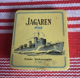 Liten ask "Jagaren", Svenska Tobaksmonopolet. Höjd 8 cm, bredd 7,5 cm, djup 1,5 cm. Lite tejprester, annars gott skick. 25 SEK