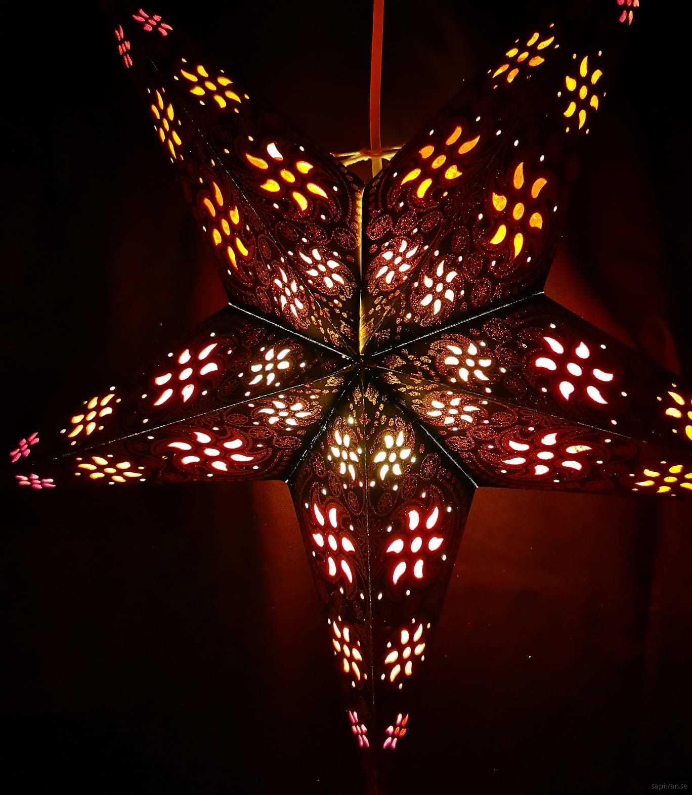 Svart, orientalisk julstjärna med varm, mysigt sken.