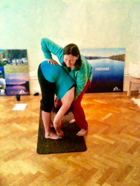 Minanda korrigerar och hjälper elev att gå djupare in i Padhangustasana Minanda korrigerar och hjälper elev att gå djupare in i Padhangustasana