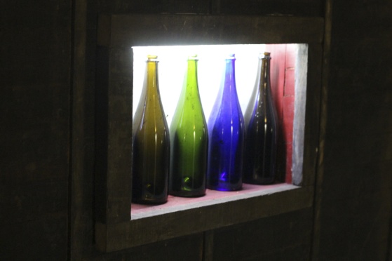 Champagneflaskor i regnbågens färger upplysta som dekoration i den nya vinkällaren.