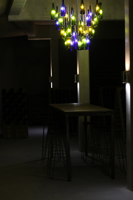 Snygg designad lampa med Champagne Mathelins egna flaskor inne i provrummet i vinkällaren.