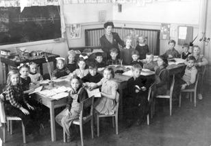 Våren 1948. Claes i första klass, Skövde Folkskola utmed Torggatan. 24 mars på tavlan. Den lilla lådan t.v i bilden innehållande diverse djur i trä, kor,grisar,hönor, några lantliga hus och buskar.