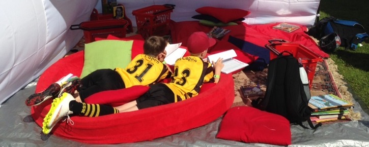 Läsande barn som tar en paus från fotbollen. Med Teamreader på Aroscupen sommaren 2015. Läsande barn som tar en paus från fotbollen. Med Teamreader på Aroscupen sommaren 2015.