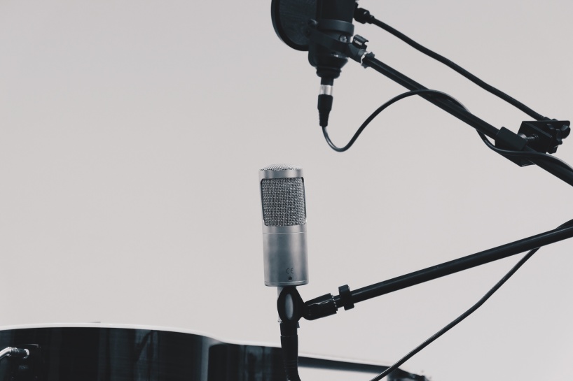 Syntolkning: Två mikrofoner, en svart och en silverfärgad, mot en vit bakgrund.