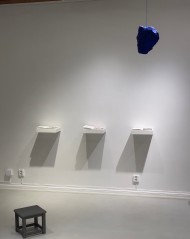 Part of installation, shelves with  handmade books, hanging blue stone and stool.