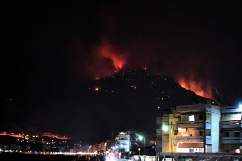 Upplysta byggnader framför ett brinnande berg under en skogsbrand cirka 80 km väster om Aten i Grekland. Bilden är från igår den 14 september 2019. EPA / VASSILIS PSOMAS Upplysta byggnader framför ett brinnande berg under en skogsbrand cirka 80 km väster om Aten i Grekland. Bilden är från igår den 14 september 2019. EPA / VASSILIS PSOMAS