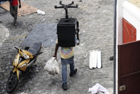 Edris Fortune/AP/TT En man i Port-au-Prince bär iväg på en stol under plundringarna av butiker i staden. Edris Fortune/AP/TT En man i Port-au-Prince bär iväg på en stol under plundringarna av butiker i staden.