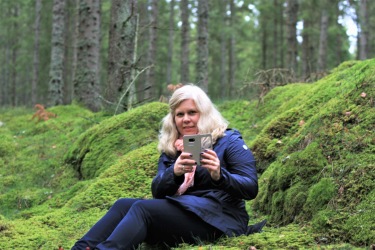 Bilden föreställer Charlotta Hurtig, digital kommunikatör på CH Digitalbyrå, som fotograferar med mobilen. Bakgrund; skog och mossa. Bilden föreställer Charlotta Hurtig, digital kommunikatör på CH Digitalbyrå, som fotograferar med mobilen. Bakgrund; skog och mossa.