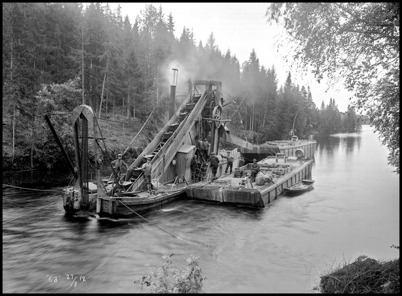 Kanalen vid Kyrkobyn i Östervallskog muddrades för att öka vattendjupet. Efter muddringen var kanalen 1,8 meter djup, vilket var tillräckligt för att den vanligaste typen av lastbåtar skulle kunna gå upp till sjön Östen i Östervallskog. Bilden togs 1912.