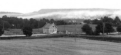 Banvaktsstugan samma år (1905) men från andra hållet med Varnhemsvägen i plankorsning, grindar och kalkrök. Delförstoring. (Skövde Stadsmuseum)
