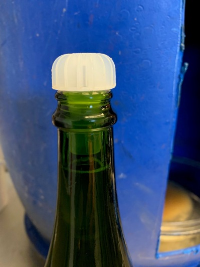 Efter påfyllnad av vin sätts en plastkork i flaskan.